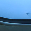 飛行機の窓の下、海面に搭乗機の影が見える